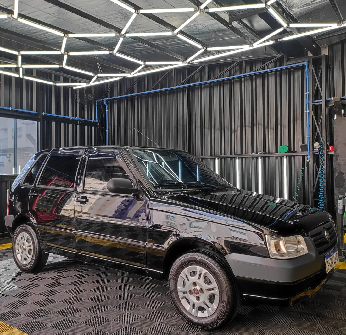 Fiat Uno preto com pintura espelhada após polimento no box